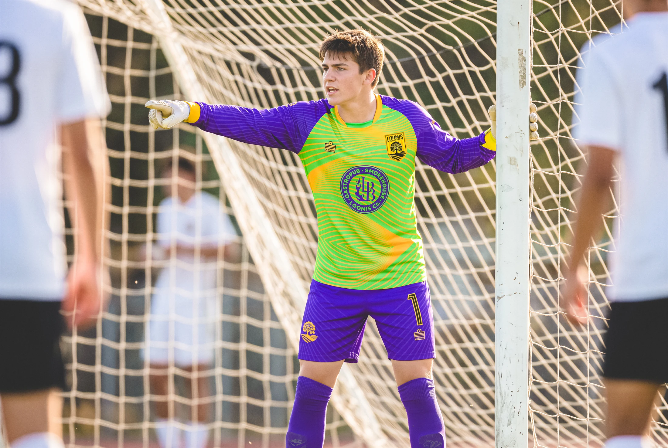 Loomis goalkeeper set in front of the net in green and purple